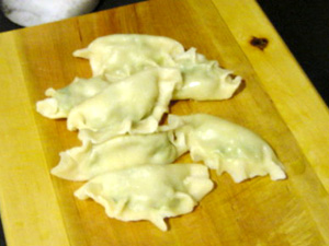 Partially cooked dumplings on a well oiled chopping board, waiting to be properly cooked in the big pot of simmering stock.